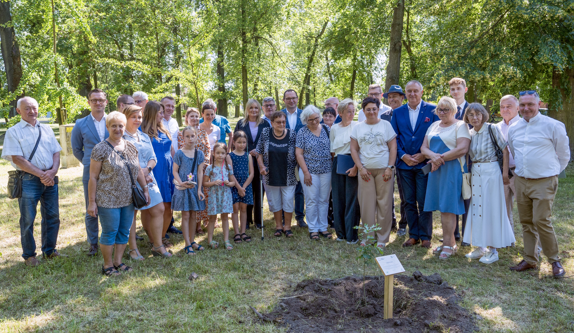 Pamiątkowe zdjęcie na zakończenie uroczystości. Fot. G.Ożga/UM Gliwice ludzie w półkręgu przy dębie