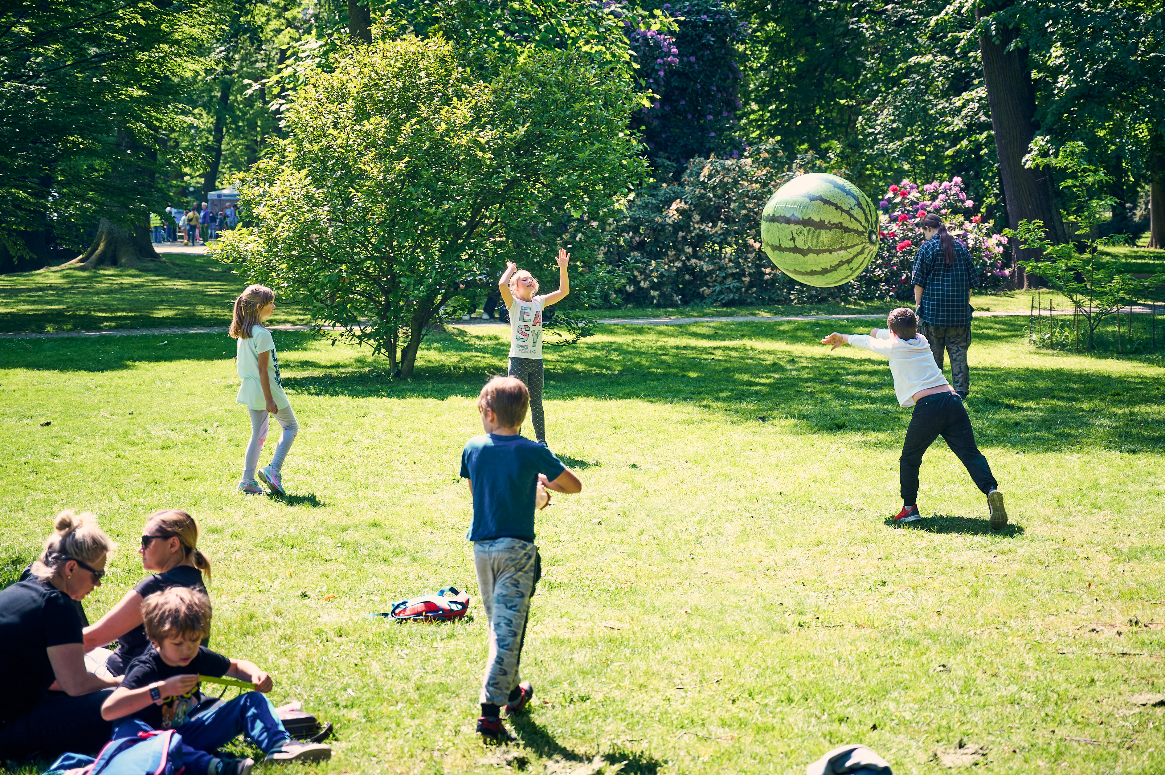 Dzieci bawiące się na trawie dmuchaną piłką