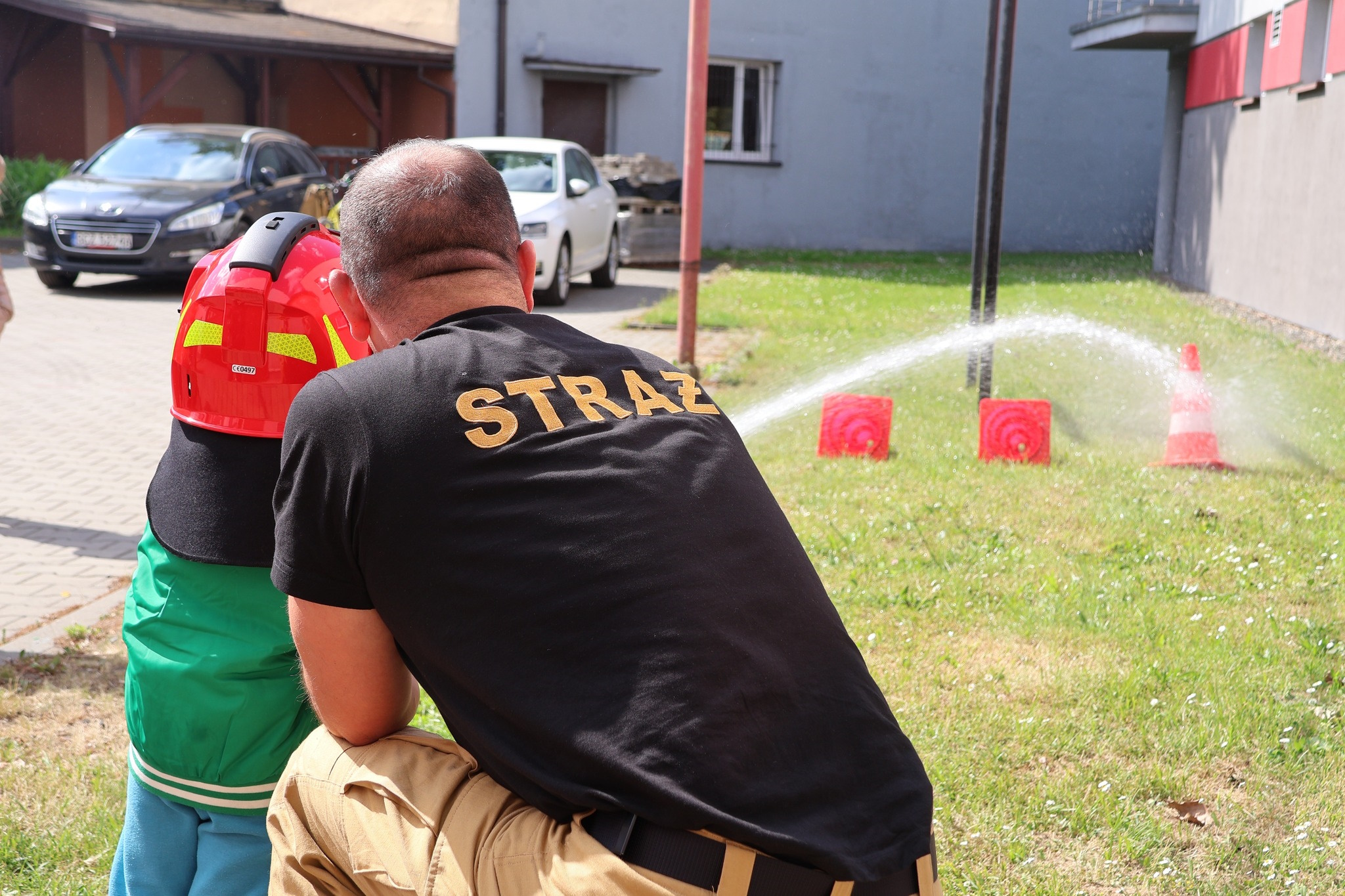 strażak uczy dziecko lać wodę z węża