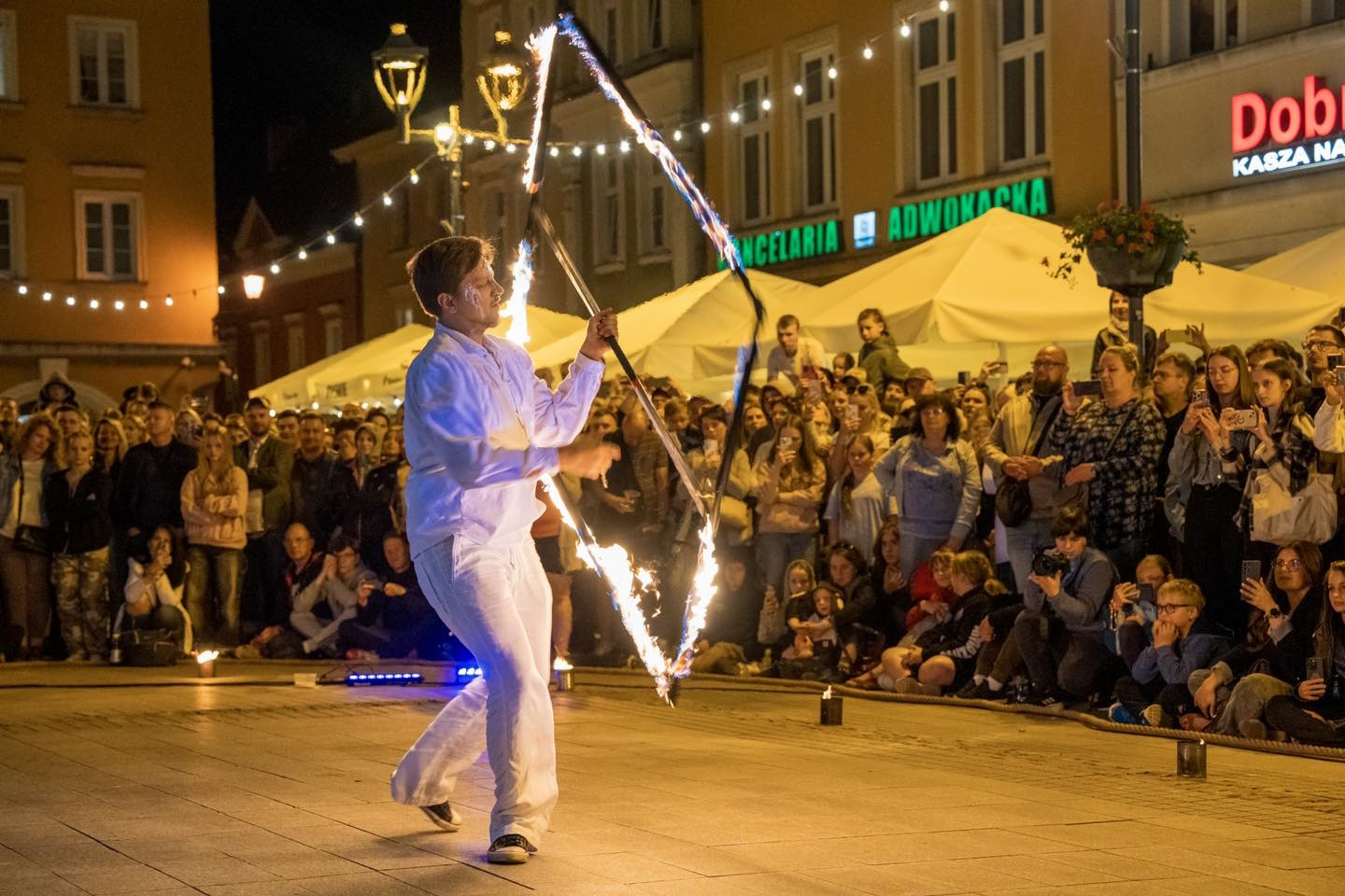 artysta ze świecącą konstrukcją, wokół ludzie, Rynek. 