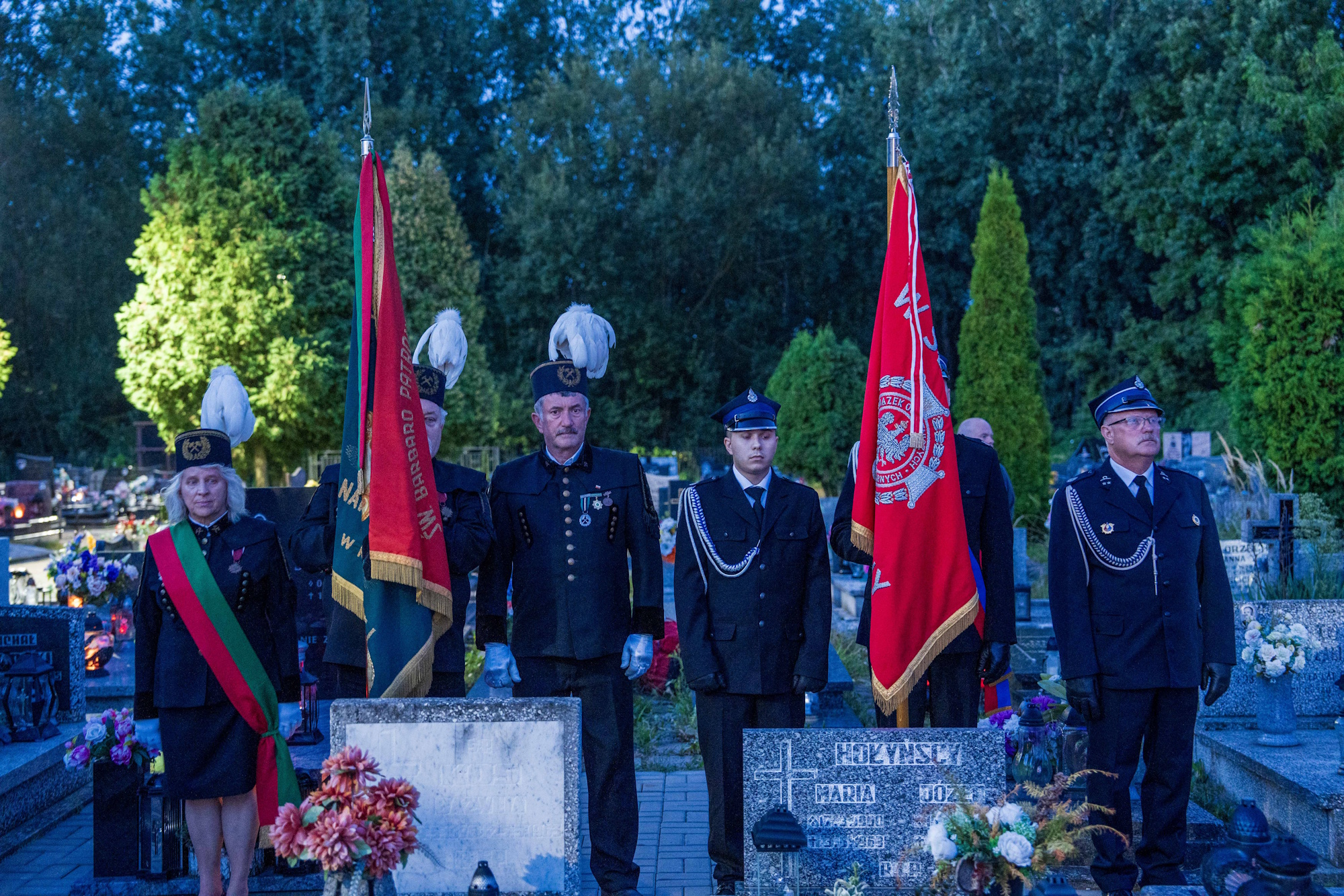 ludzie ze sztandarami na cmentarzu