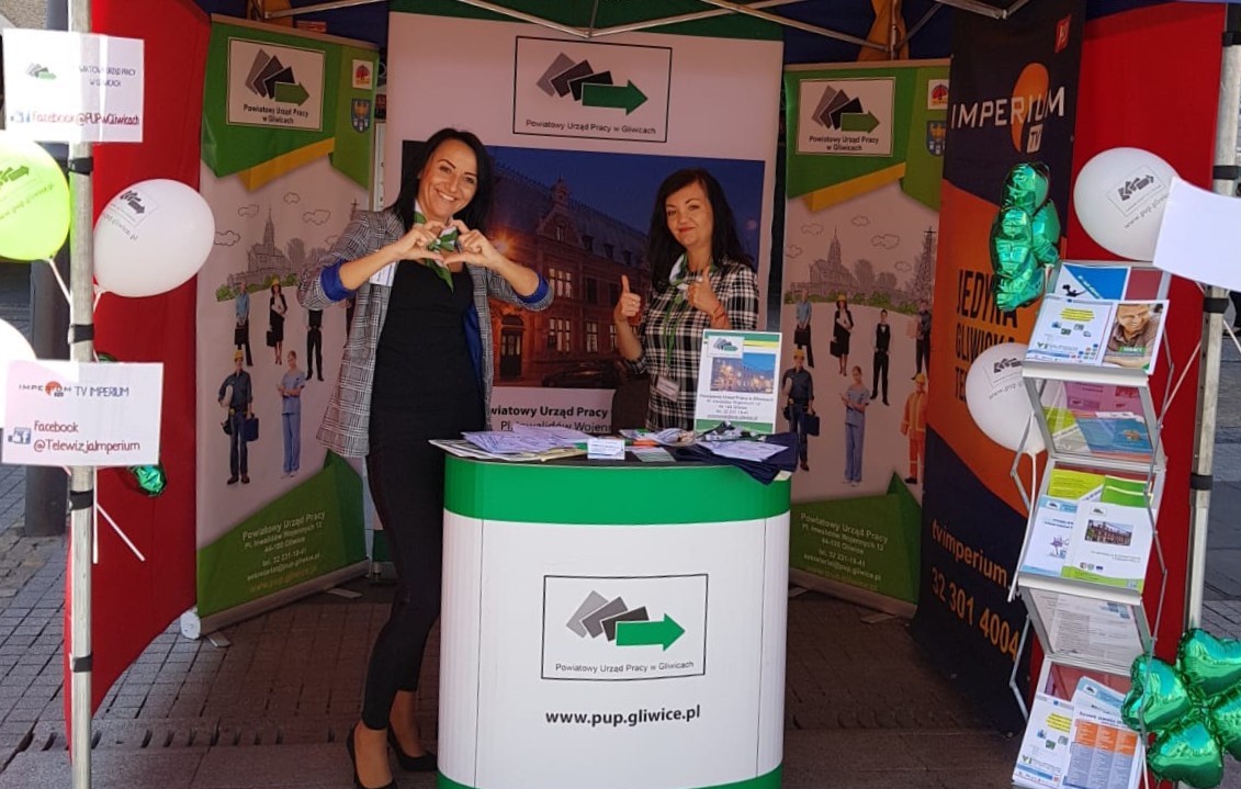 Pracownice Powiatowego Urzędu Pracy w Gliwicach uśmiechające się przy stoisku