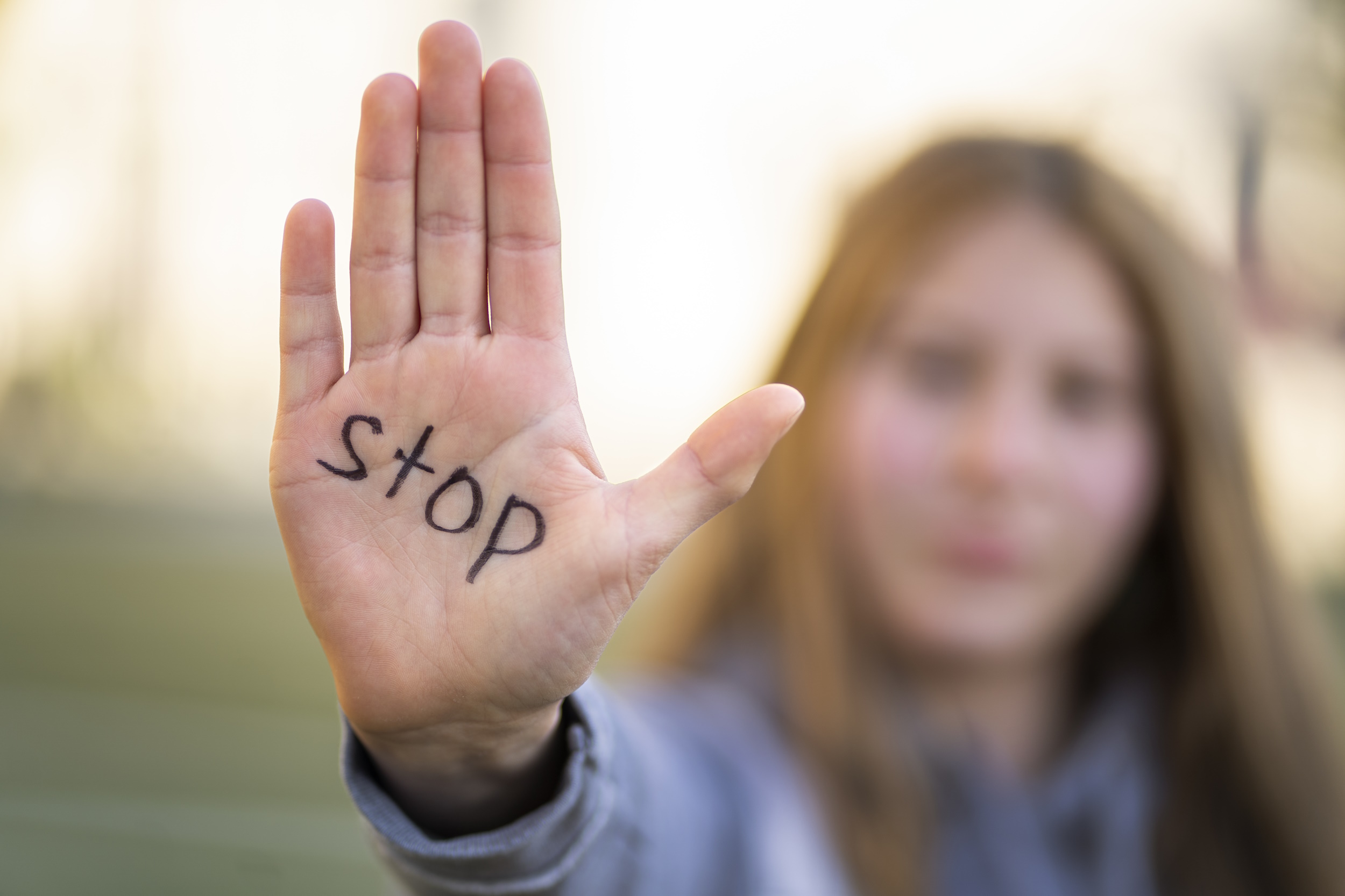 Zdjęcie kobiety, a z przodu otwarta dłoń z napisem stop